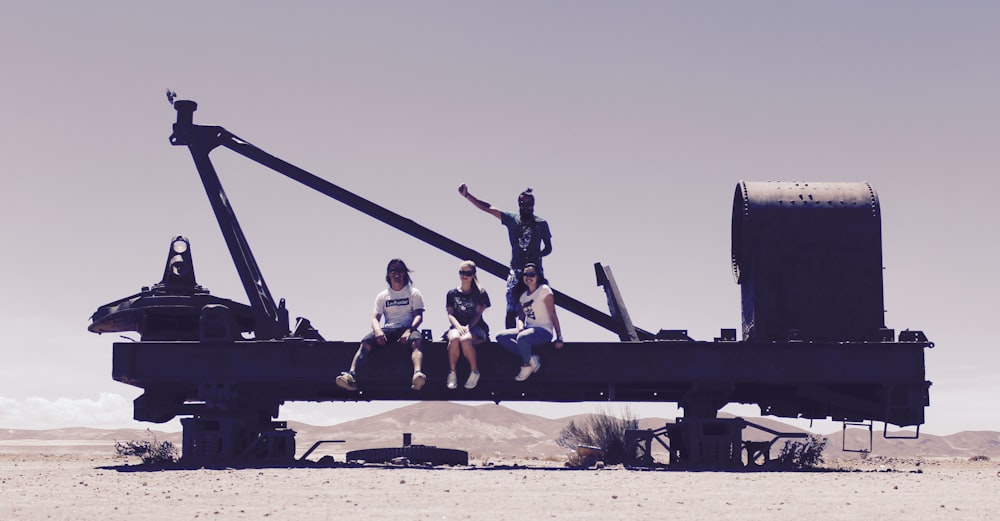 3 men sitting on black metal crane during daytime