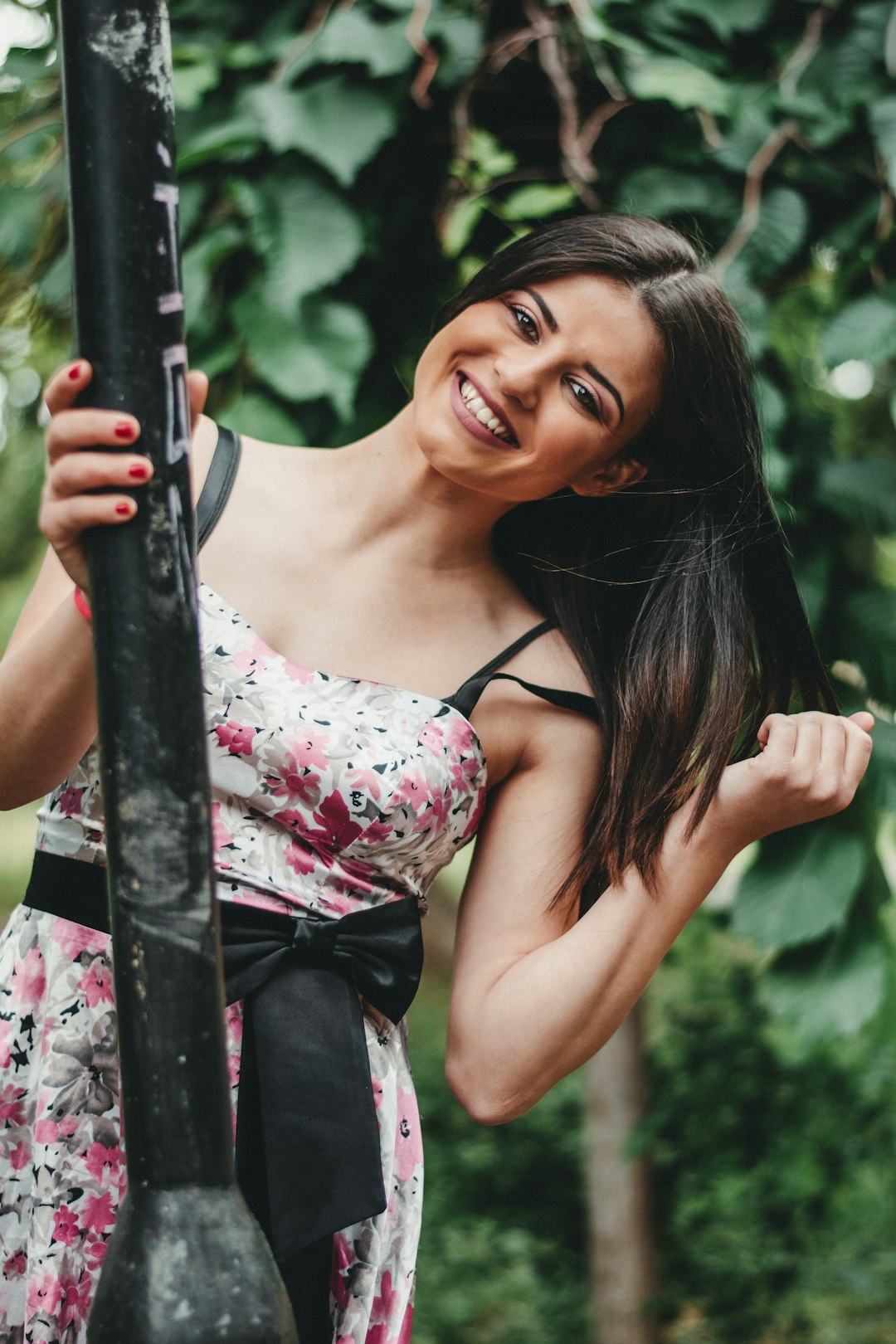 woman in white and pink floral spaghetti strap top holding black metal bar