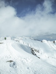 Hiker walking towards a snowy glacier with mountains and blue sky in Ushuaia.