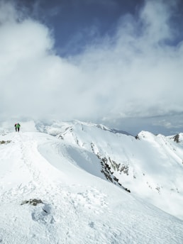 Hiker walking towards a snowy glacier with mountains and blue sky in Ushuaia.
