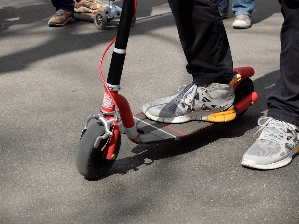 person in black pants and black red and white sneakers riding red and black ride on m