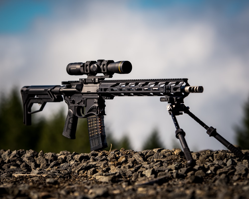 Schwarzes Gewehr mit Zielfernrohr auf braunem Boden