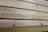 Close-up view of several neatly stacked wooden planks exhibiting natural grain patterns and a light tan color, indicative of unfinished or lightly finished wood.
