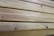 Close-up view of several neatly stacked wooden planks exhibiting natural grain patterns and a light tan color, indicative of unfinished or lightly finished wood.