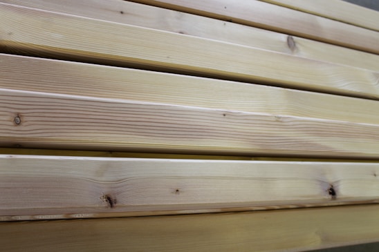 Close-up view of several neatly stacked wooden planks exhibiting natural grain patterns and a light tan color, indicative of unfinished or lightly finished wood.