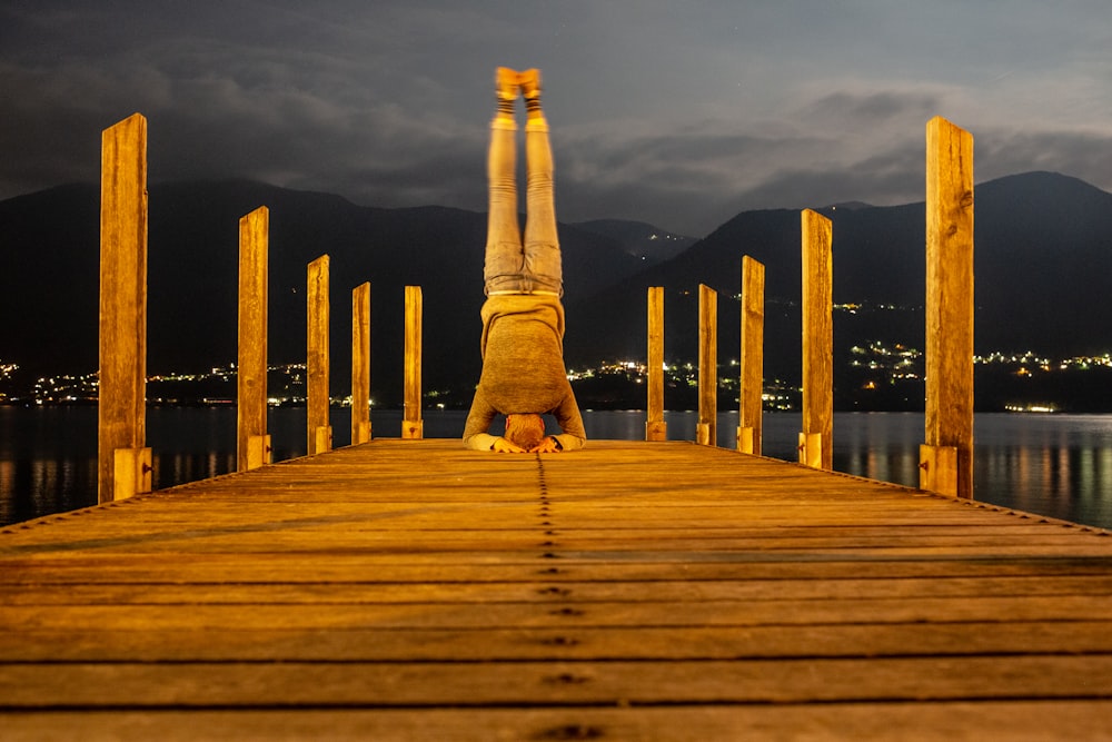 person in brown pants sitting on brown wooden dock during daytime