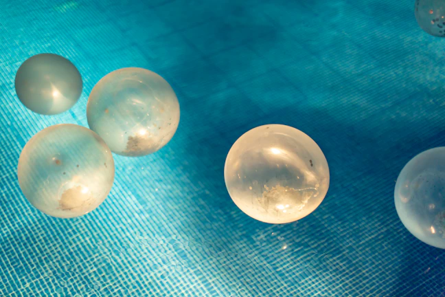 Close-up of floating photocatalyst spheres glistening on a water surface under sunlight.