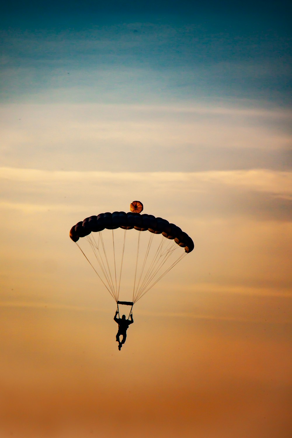 person in parachute under white clouds during daytime