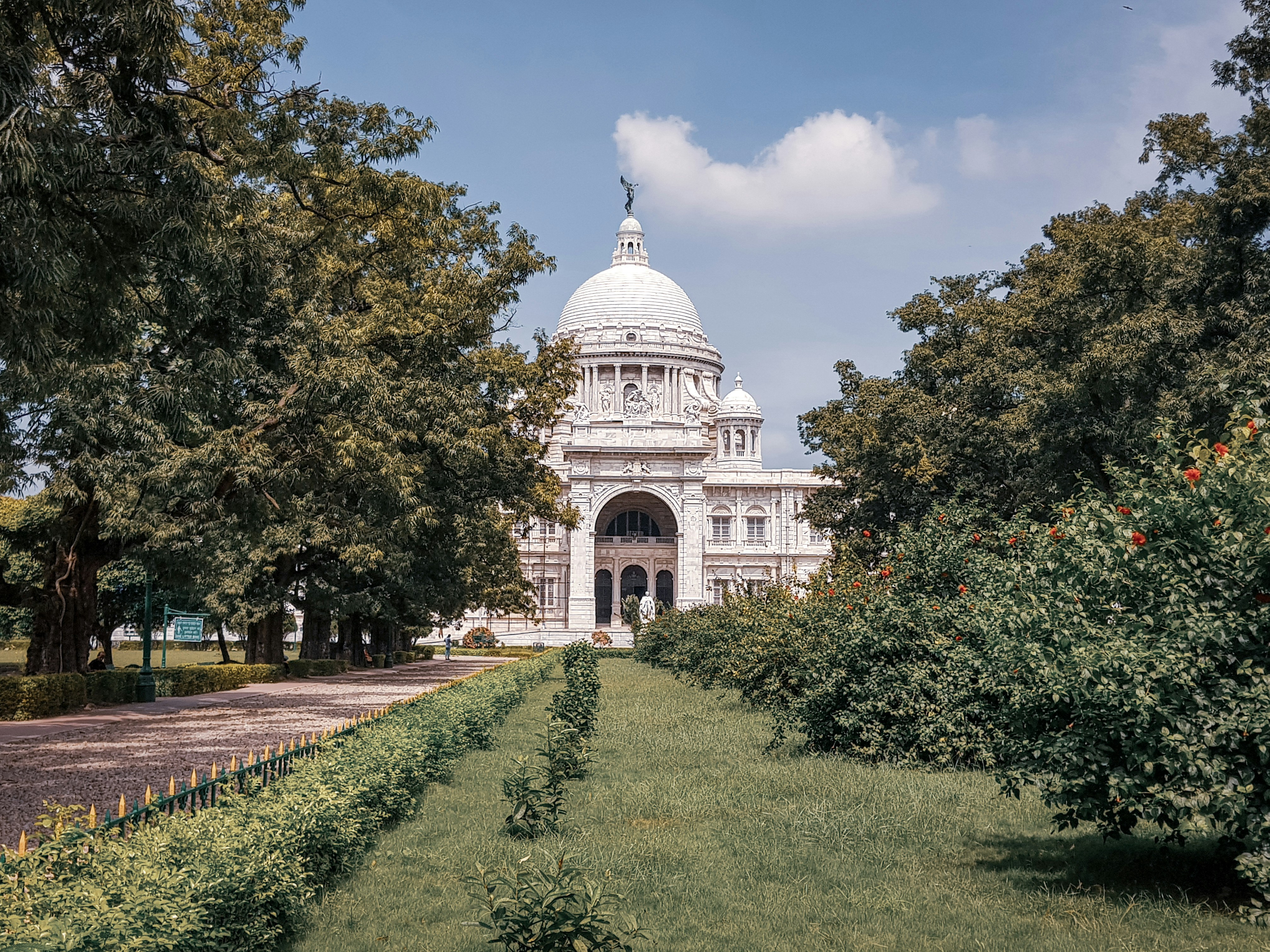 edificio in cemento bianco vicino agli alberi verdi sotto il cielo blu durante il giorno