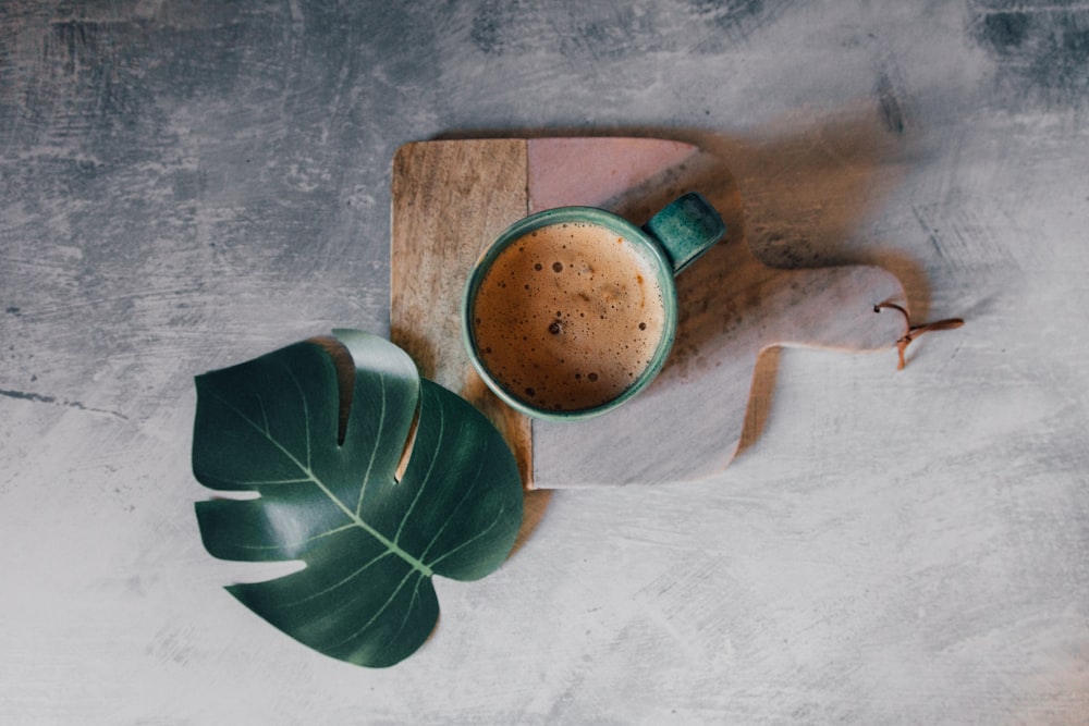 brown ceramic mug with brown liquid on brown wooden chopping board