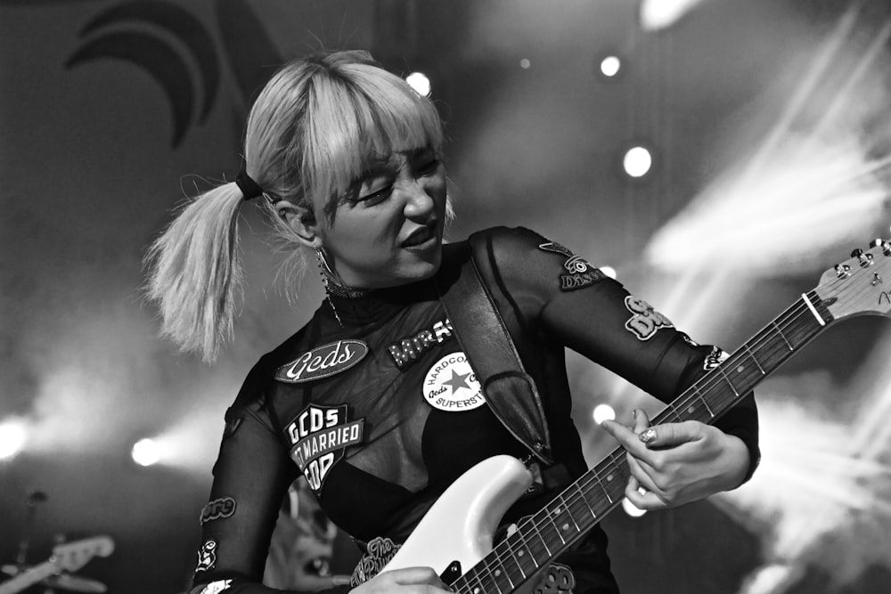 woman in black and white shirt playing electric guitar