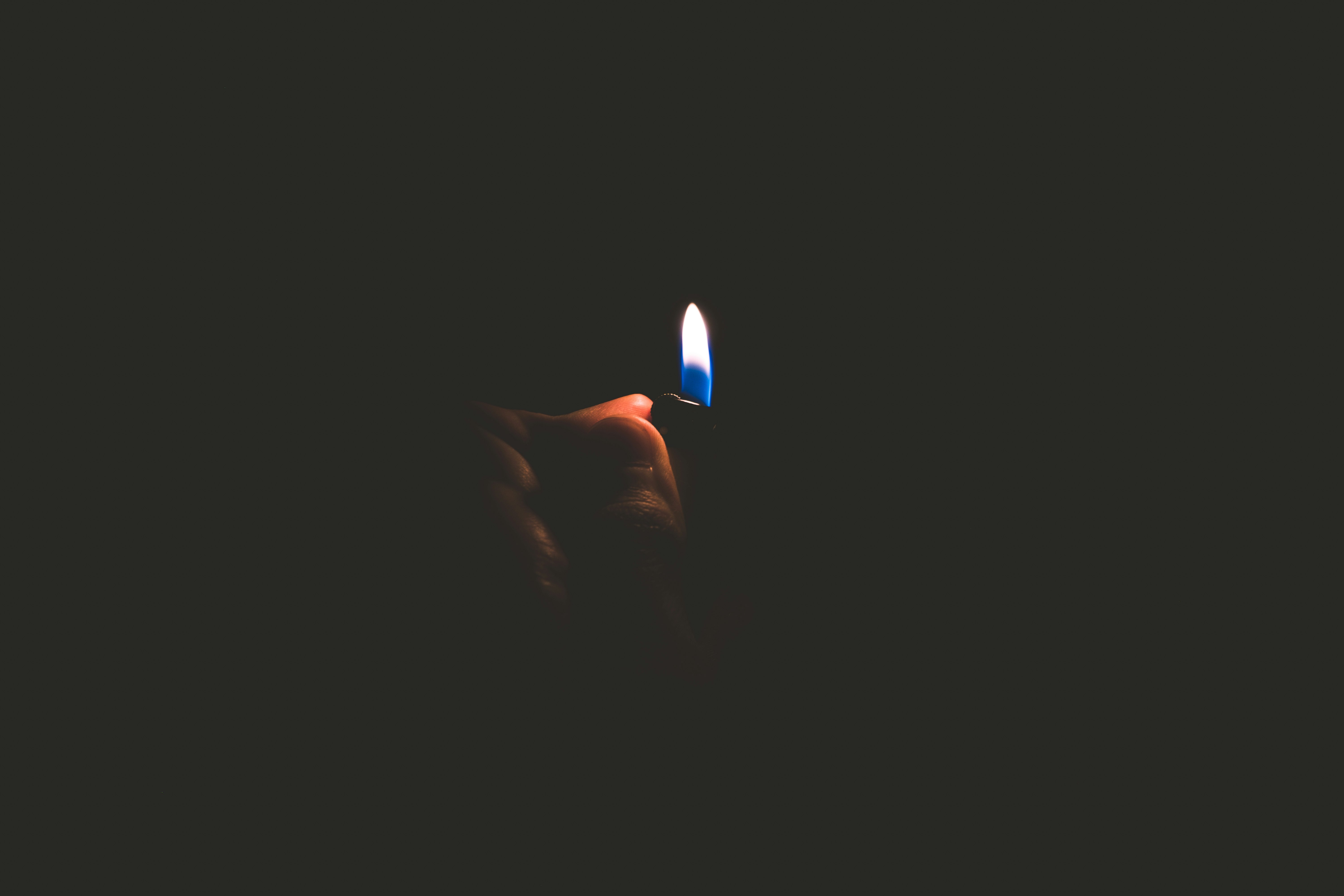 person holding lighted lighter with black background
