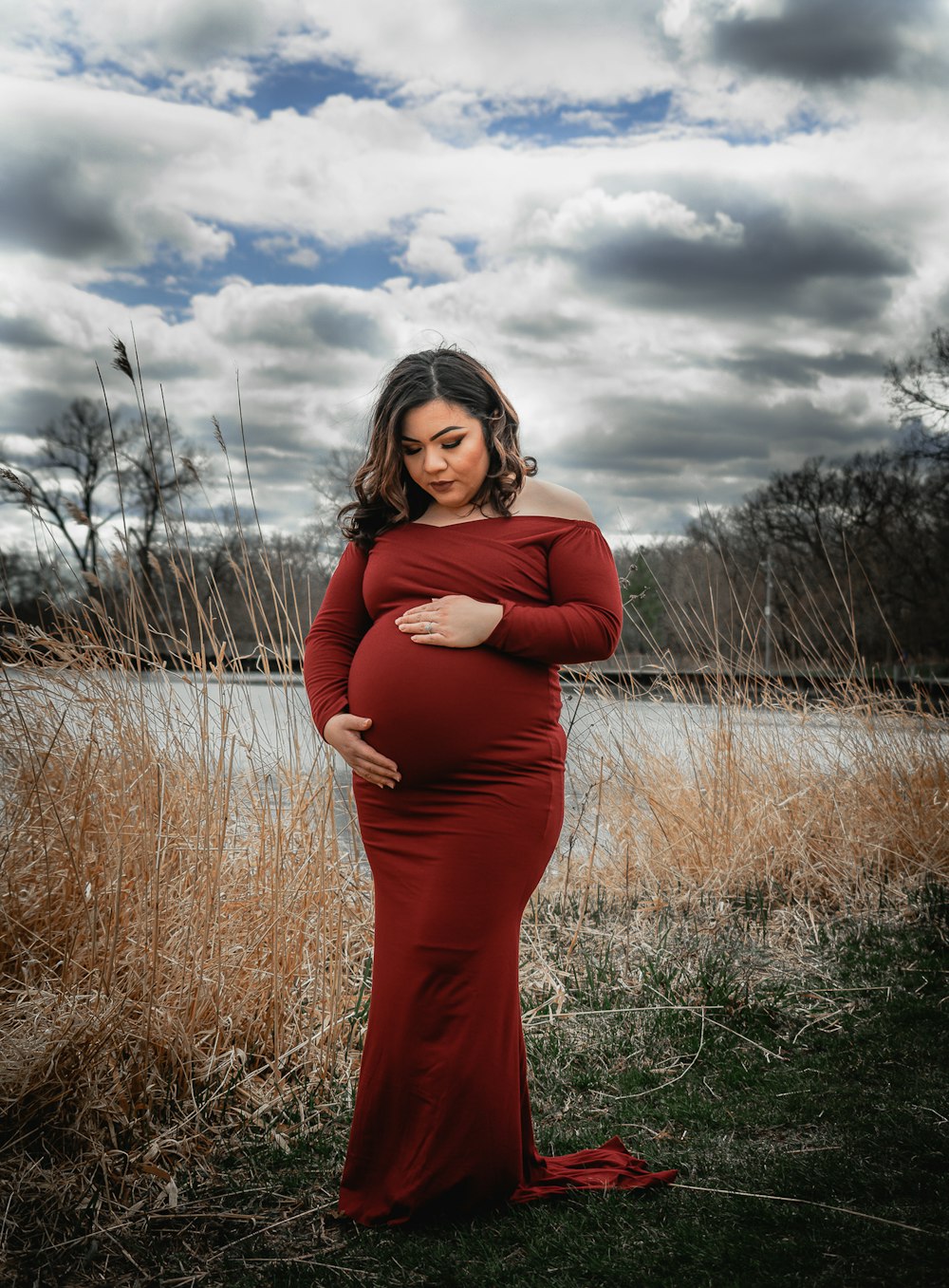 woman in red long sleeve dress standing on green grass field under white clouds during daytime