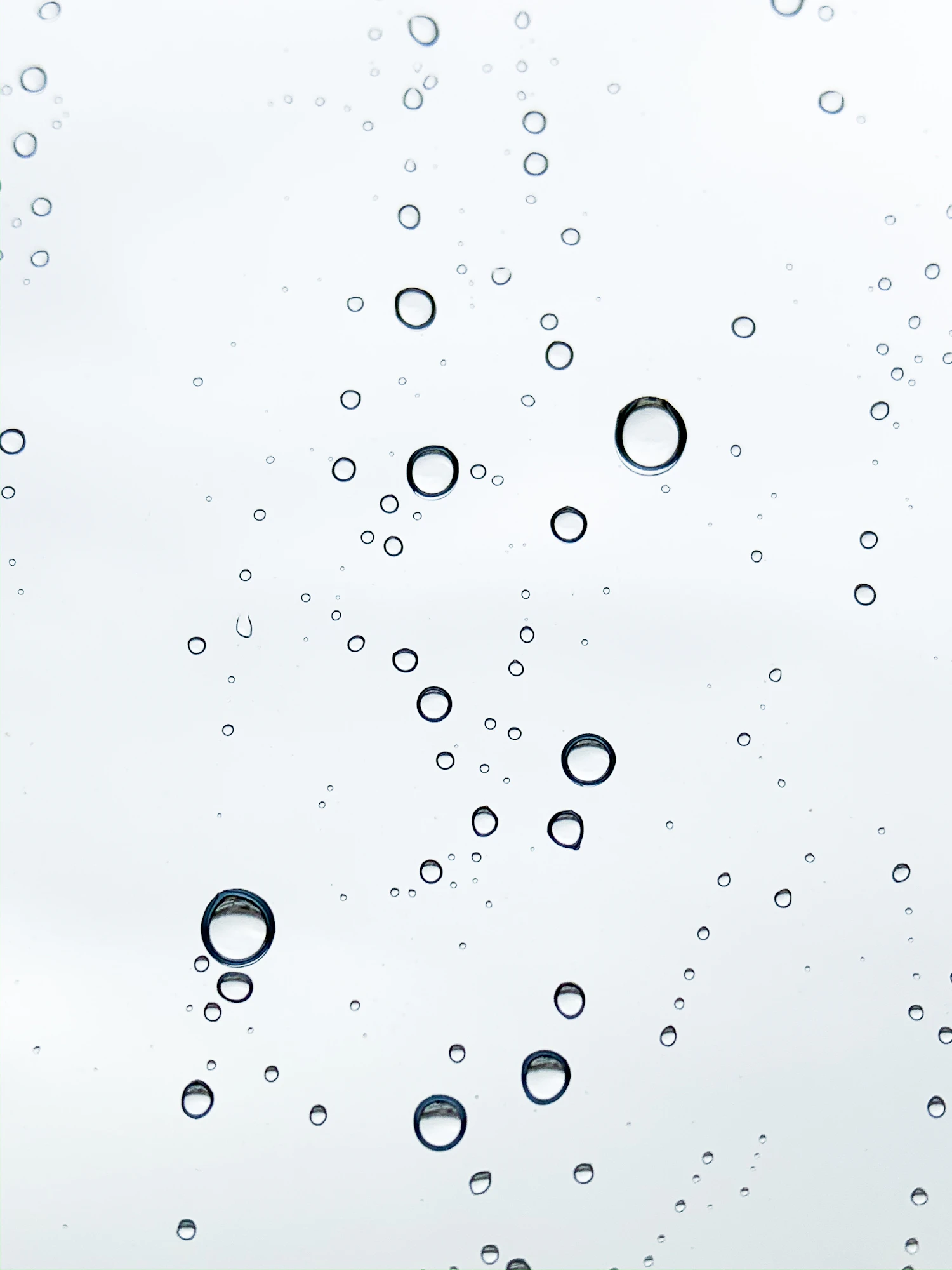 Water droplets beaded on a pale glass panel