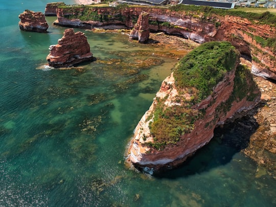 brown and green rock formation on body of water during daytime in Ladram Bay United Kingdom