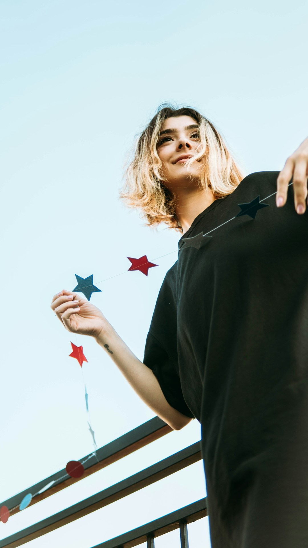 smiling woman in black polo shirt holding red and white star flag