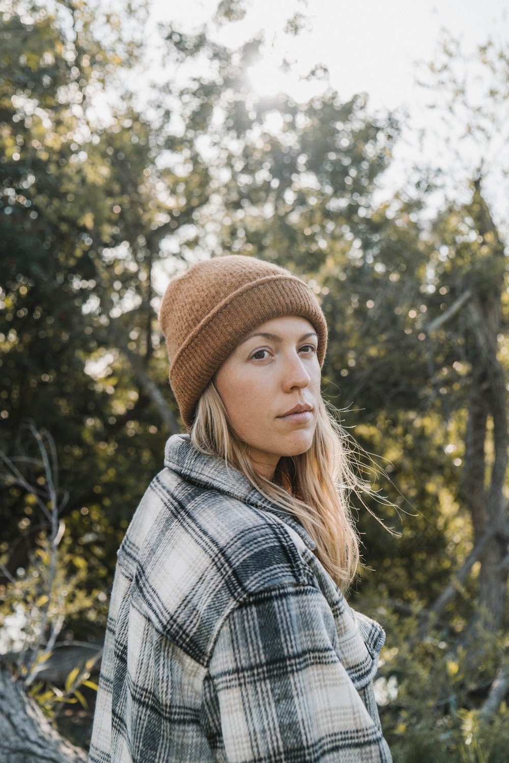 Mujer con gorra de punto marrón y camisa a cuadros