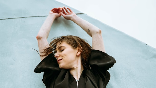 A serene woman gently stretching her arms in a sunlit room, embodying calm and strength.