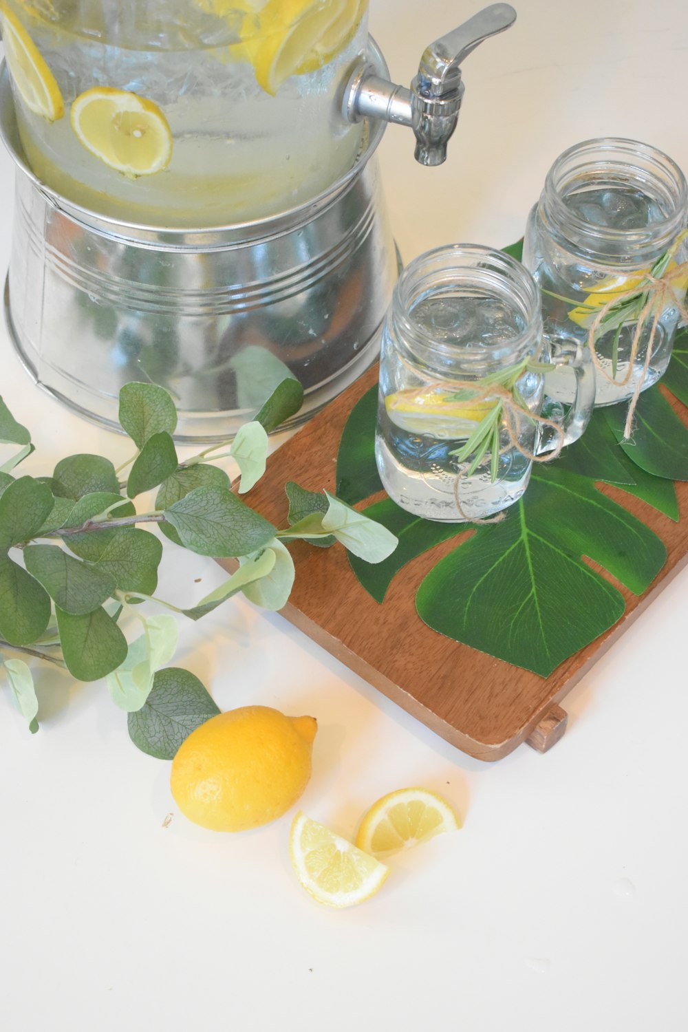 clear glass jar with green leaves beside clear glass jar with yellow liquid