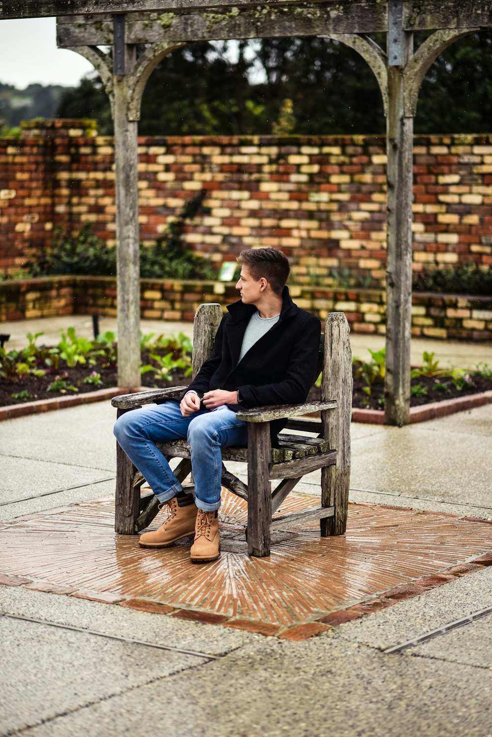 man in black suit sitting on brown wooden bench