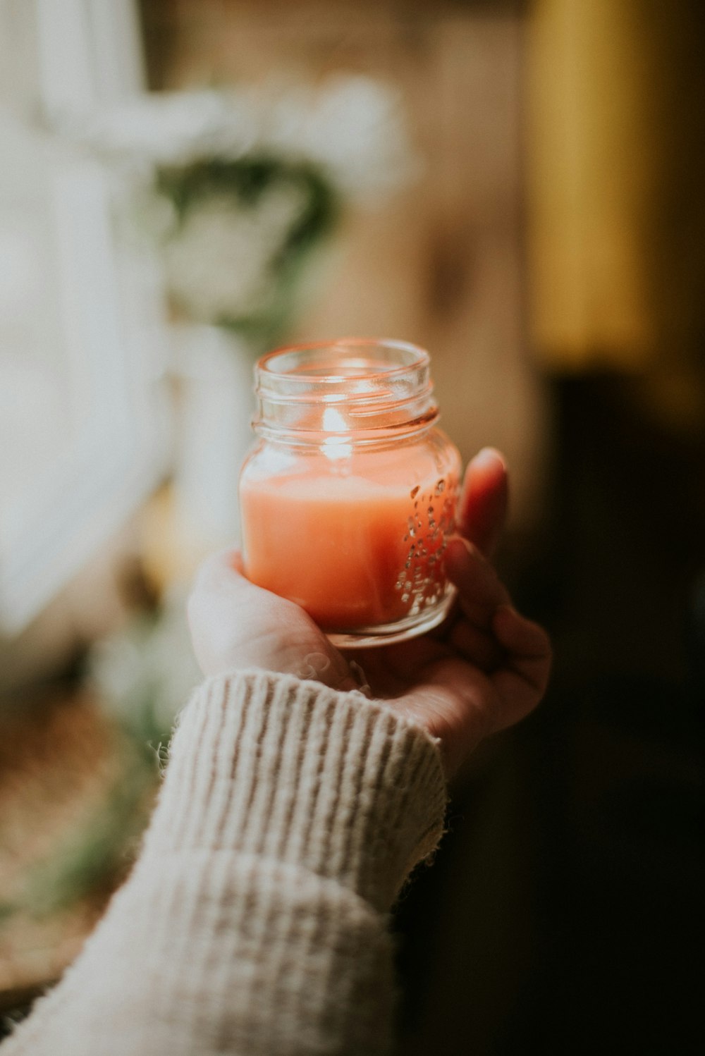 person holding clear glass candle holder with red candle