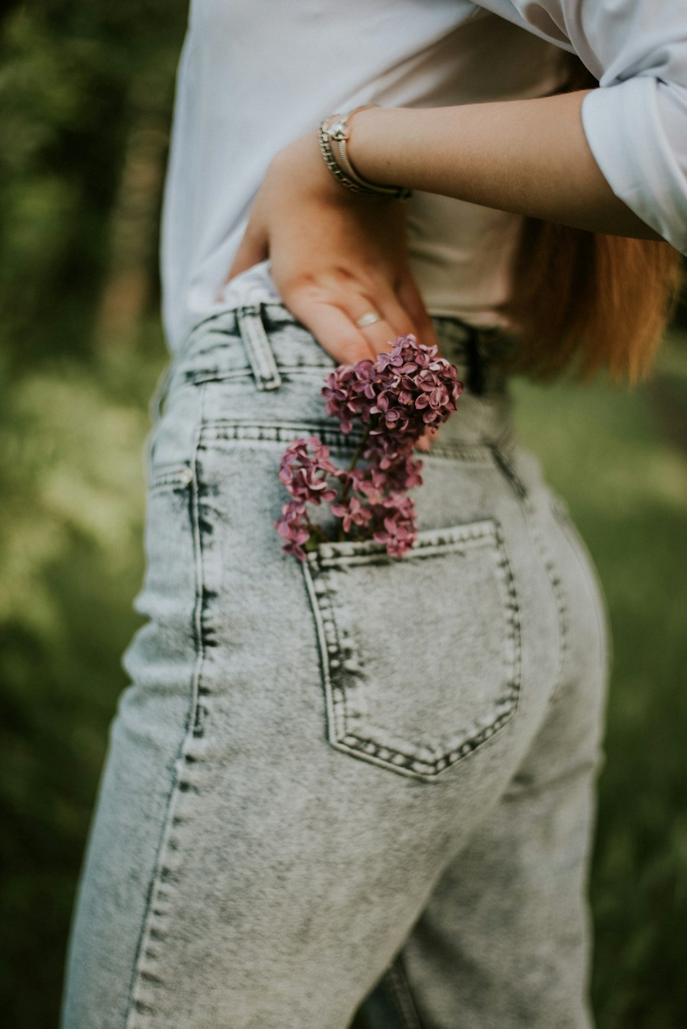 woman in gray denim jeans holding pink flower bouquet