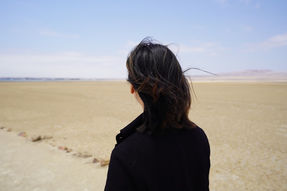 woman in black shirt standing on white sand during daytime