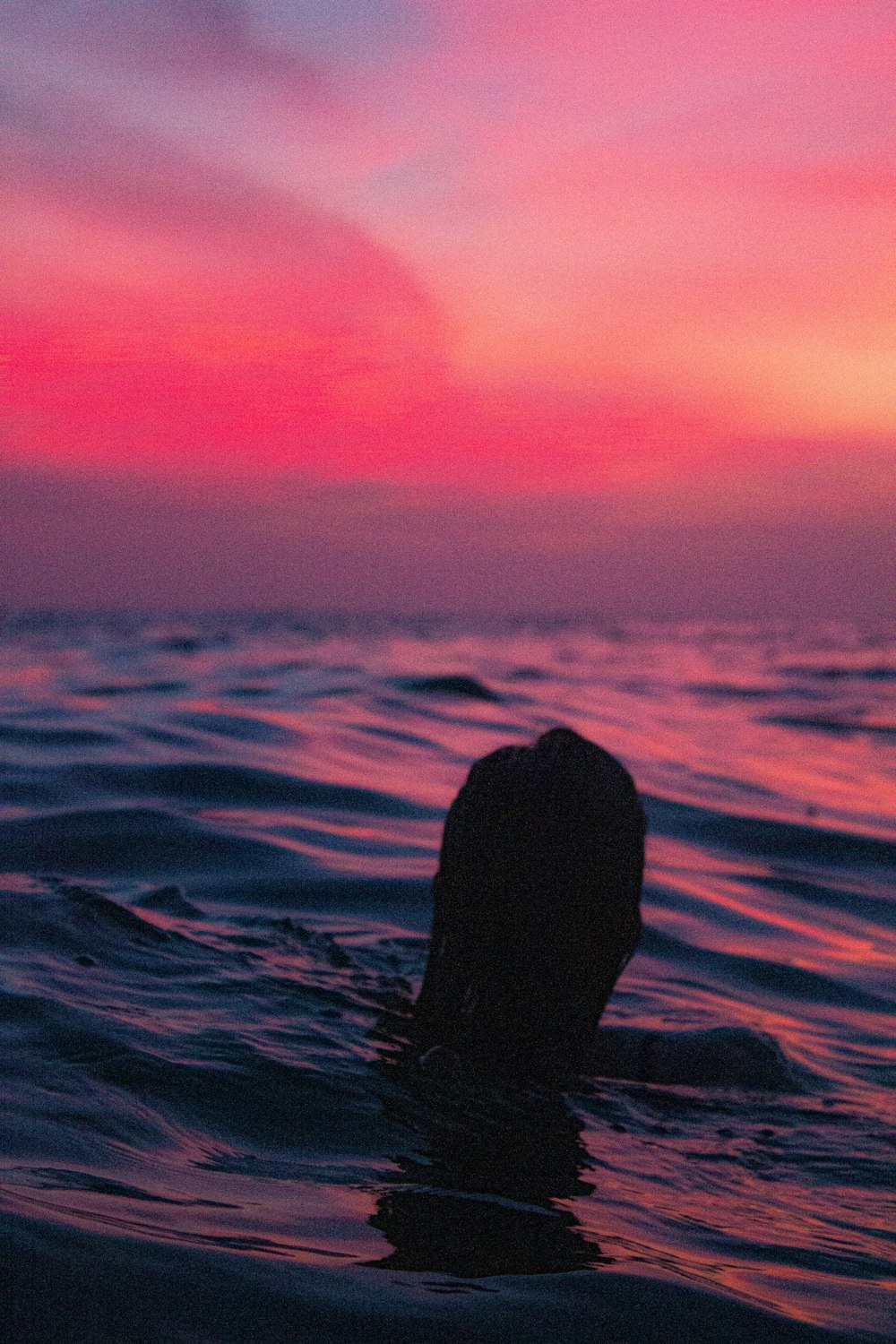 silhouette of person on body of water during sunset