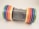 A silver Canon PowerShot S45 camera is positioned horizontally, with several colorful rolls of tape placed on either side of the camera. The tapes are arranged in an orderly fashion with the colors including green, blue, purple, red, orange, and yellow. The tapes provide a vibrant contrast to the metallic finish of the camera.