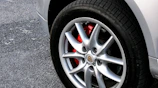 Close-up of a shiny red brake disc and caliper on a car wheel.