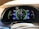 A car dashboard display showing various metrics including battery level, fuel range, odometer reading, and Bluetooth audio connectivity. The display includes indicators for power usage in kilowatts, EV range in miles, and a speedometer set to zero mph. The dashboard has a sleek, modern design with vibrant colors.
