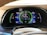 A car dashboard display showing various metrics including battery level, fuel range, odometer reading, and Bluetooth audio connectivity. The display includes indicators for power usage in kilowatts, EV range in miles, and a speedometer set to zero mph. The dashboard has a sleek, modern design with vibrant colors.