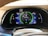 A car dashboard display showing various metrics including battery level, fuel range, odometer reading, and Bluetooth audio connectivity. The display includes indicators for power usage in kilowatts, EV range in miles, and a speedometer set to zero mph. The dashboard has a sleek, modern design with vibrant colors.