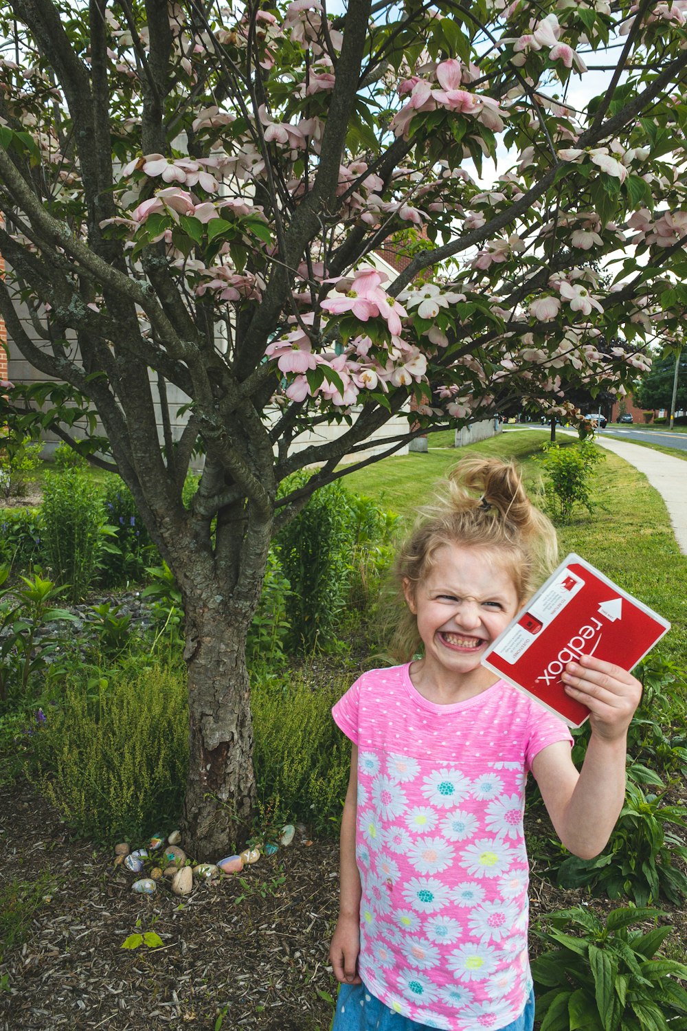 girl in pink and white crew neck t-shirt holding red and white box