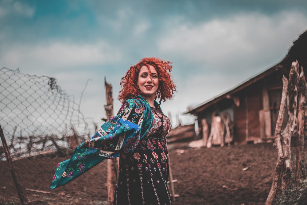 woman in black and red floral dress standing on brown field during daytime