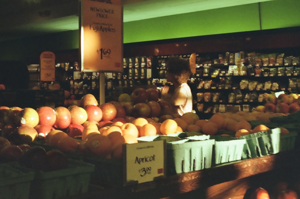 woman in black jacket sitting on brown wooden bench with orange fruits on top