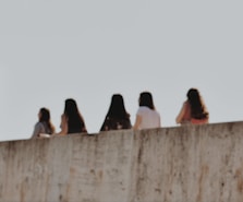 people sitting on concrete wall during daytime