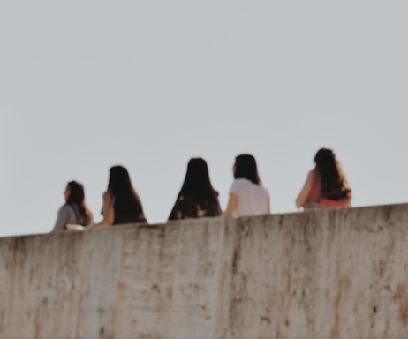 people sitting on concrete wall during daytime