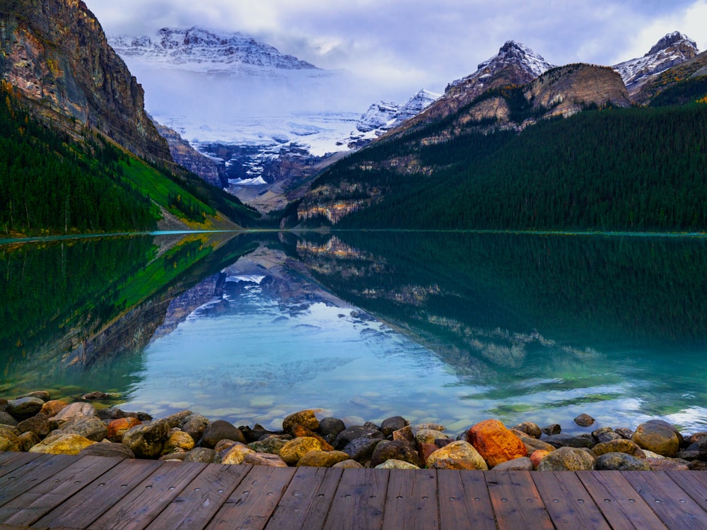 green and brown mountains beside lake under white clouds and blue sky during daytime