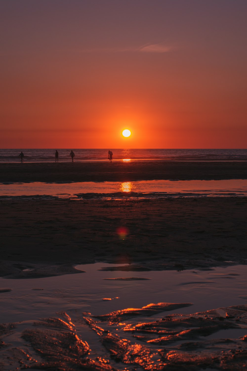 Silhouette von Menschen am Strand während des Sonnenuntergangs