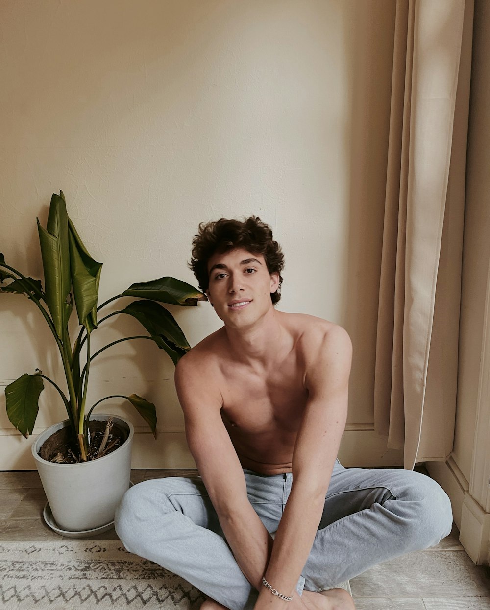 topless man in blue denim jeans sitting on gray sofa chair