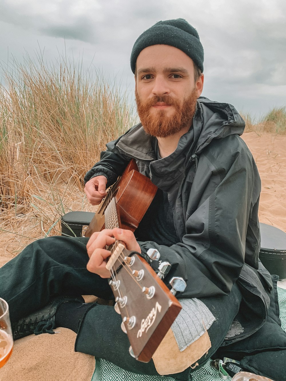 man in black jacket playing brown acoustic guitar