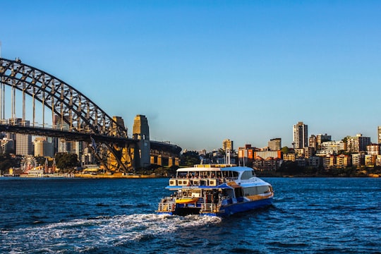 white and blue boat on sea near bridge during daytime in Sydney Harbour Bridge Australia
