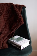 A finished chunky knit blanket draped over a chair.