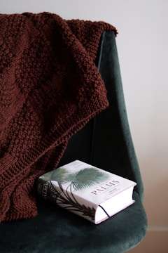 A finished chunky knit blanket draped over a chair.