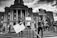 A group of people stands in front of a large government building, holding signs advocating for racial equality and an end to police brutality. The scene is lively with people engaged in peaceful protest. The building in the background features grand columns and intricate architectural details.