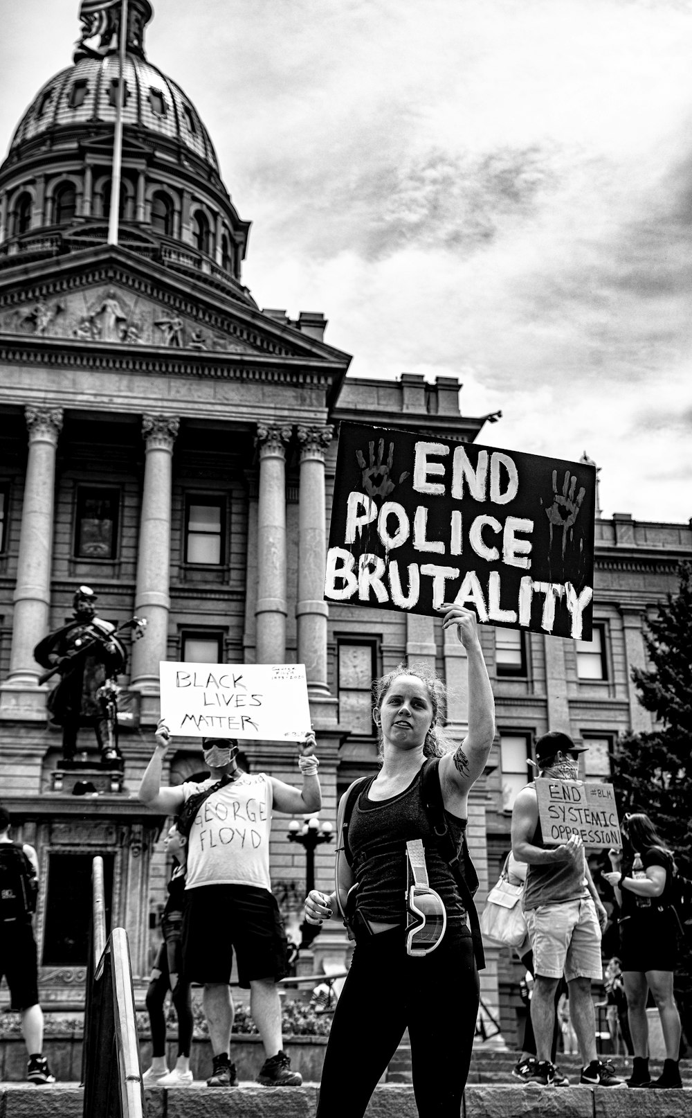 grayscale photo of man and woman holding signage