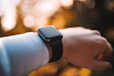 An action shot of a smart watch on a wrist during a morning jog in a sunlit park.