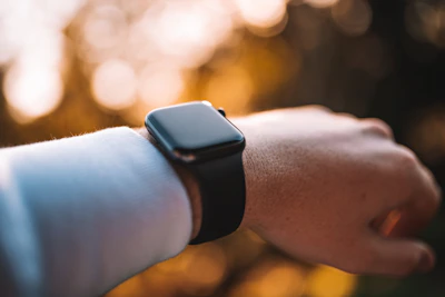 An action shot of a smart watch on a wrist during a morning jog in a sunlit park.