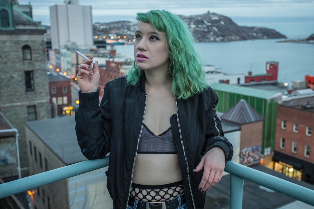 woman in black jacket standing beside blue metal railings during daytime